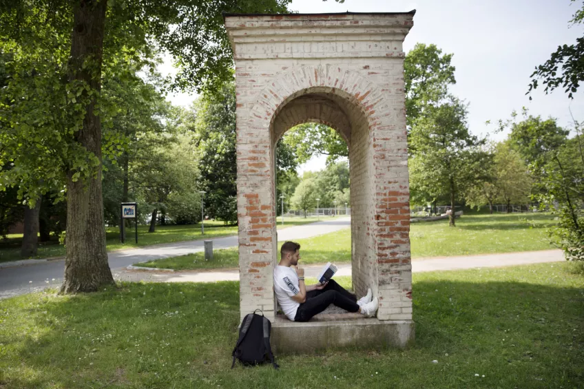Fotografi av en student som sitter i en park och studerar